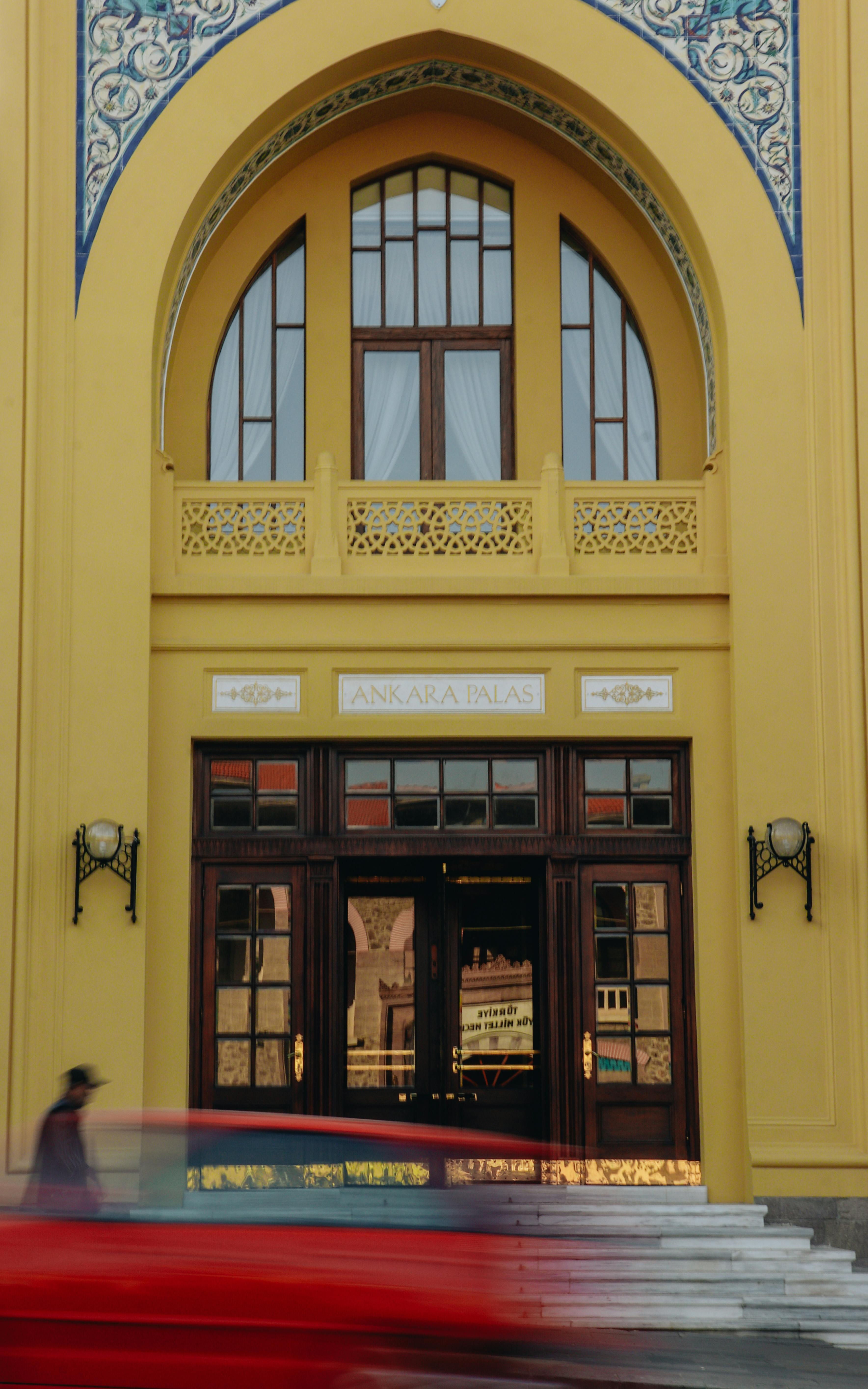 Free A blurry red object passes by the ornate entrance of the historic Ankara Palace in Turkey. Stock Photo