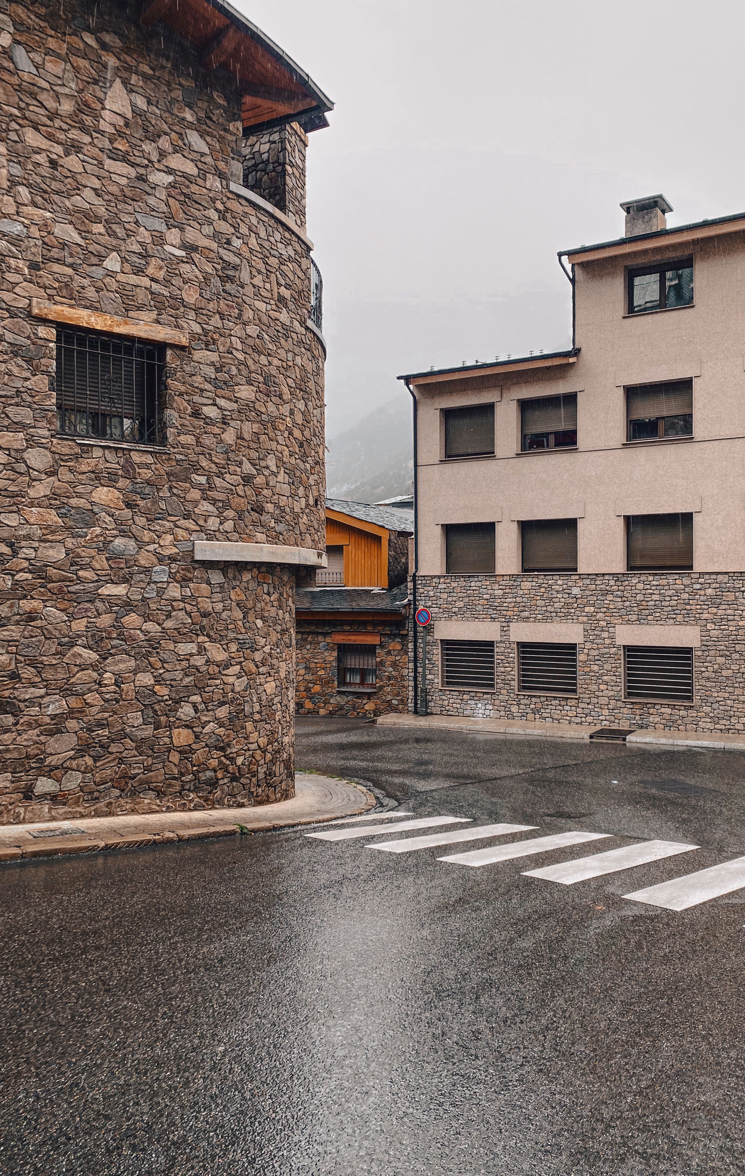 A quaint street scene in Andorra la Vella with traditional stone buildings and a pedestrian crossing.