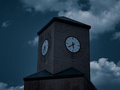 Free A striking brick clock tower at night with moody clouds overhead. Stock Photo
