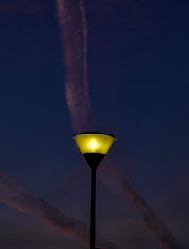 A glowing streetlight against a dusky sky with contrails in Durrës, Albania.