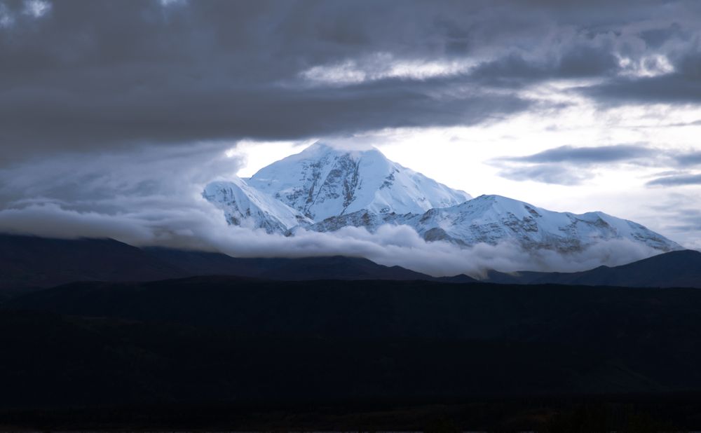 Pico nevado del Denali asomando entre nubes dramáticas