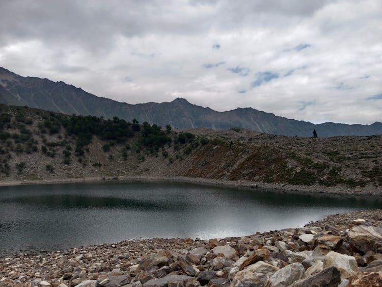 Lake Near Mountain Under Cloudy Sky