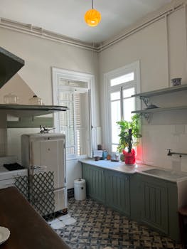 A charming vintage kitchen with retro appliances and natural light through tall windows.