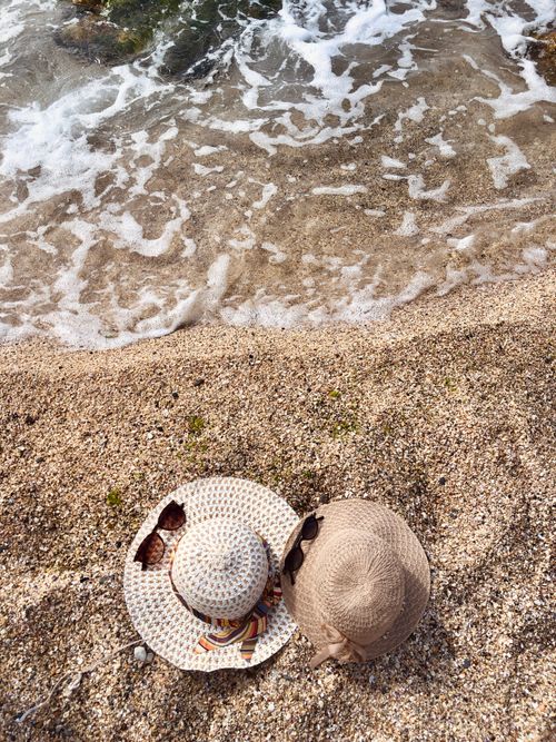 Free Two stylish sun hats resting on a sandy beach by the wave-swept shore in Arnavutköy, Istanbul. Stock Photo