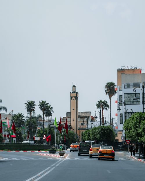 Free Street scene in Ouezzane, Morocco, showcasing urban life, architecture, and vibrant flags. Stock Photo