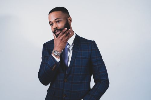 Free Stylish man in a plaid suit posing thoughtfully in a studio setting. Stock Photo