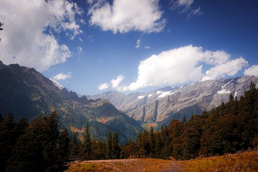 Breathtaking autumn landscape view of Manali's mountain ranges with vibrant foliage and blue skies.