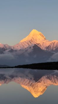 Stunning snowcapped mountain reflecting on calm water at sunrise, capturing the essence of winter serenity.
