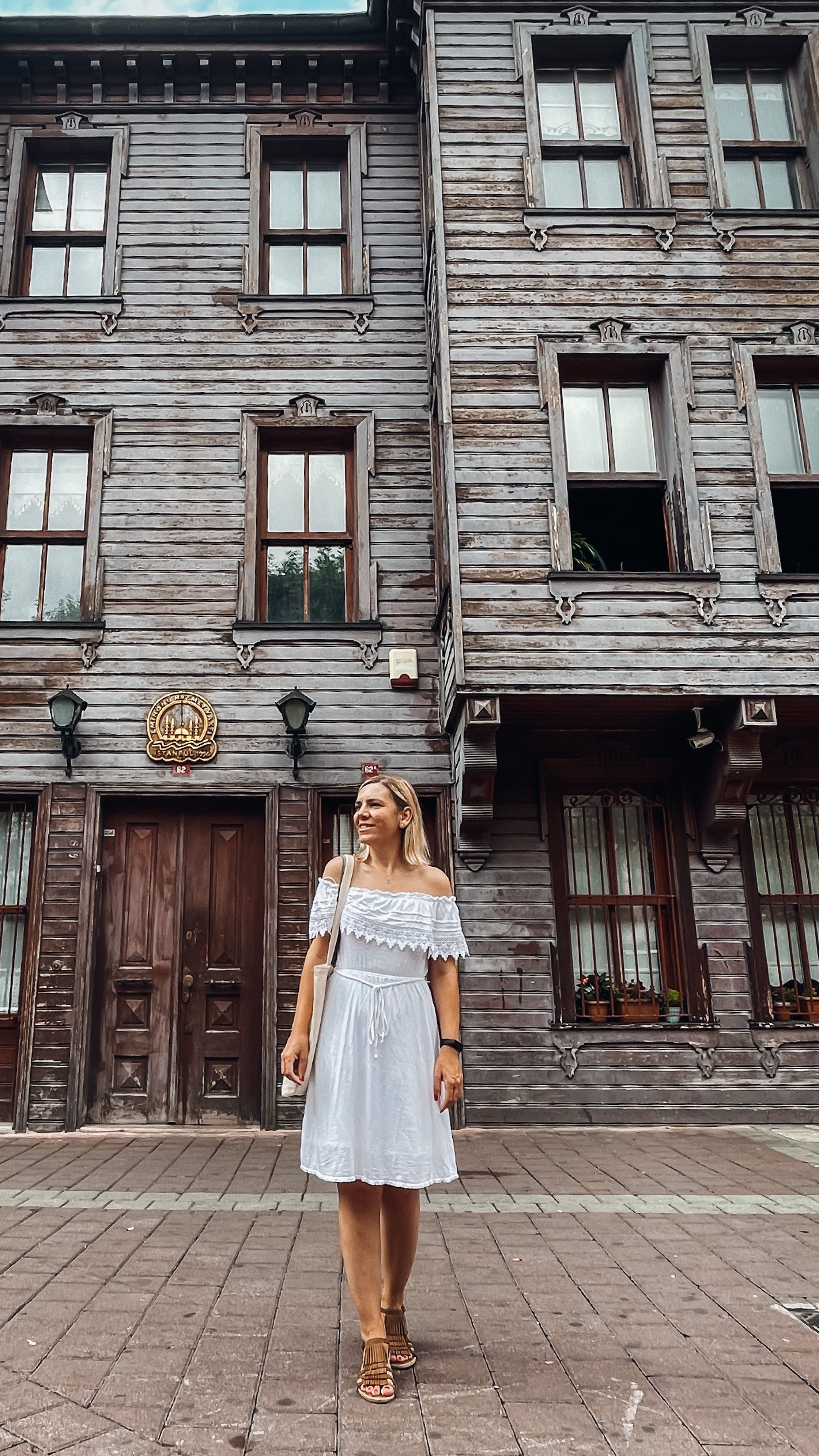Blonde woman standing in front of a historic wooden house in Istanbul, Turkey.
