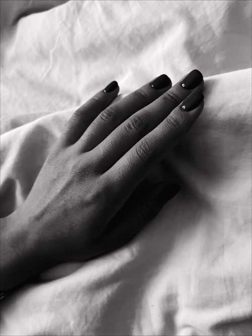 Free A detailed black and white capture of a hand with nail art on a soft fabric background. Stock Photo