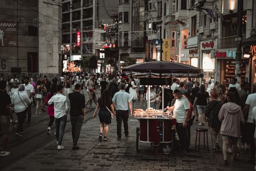 Crowded Istanbul street with vendors and pedestrians under city lights, showcasing urban life.