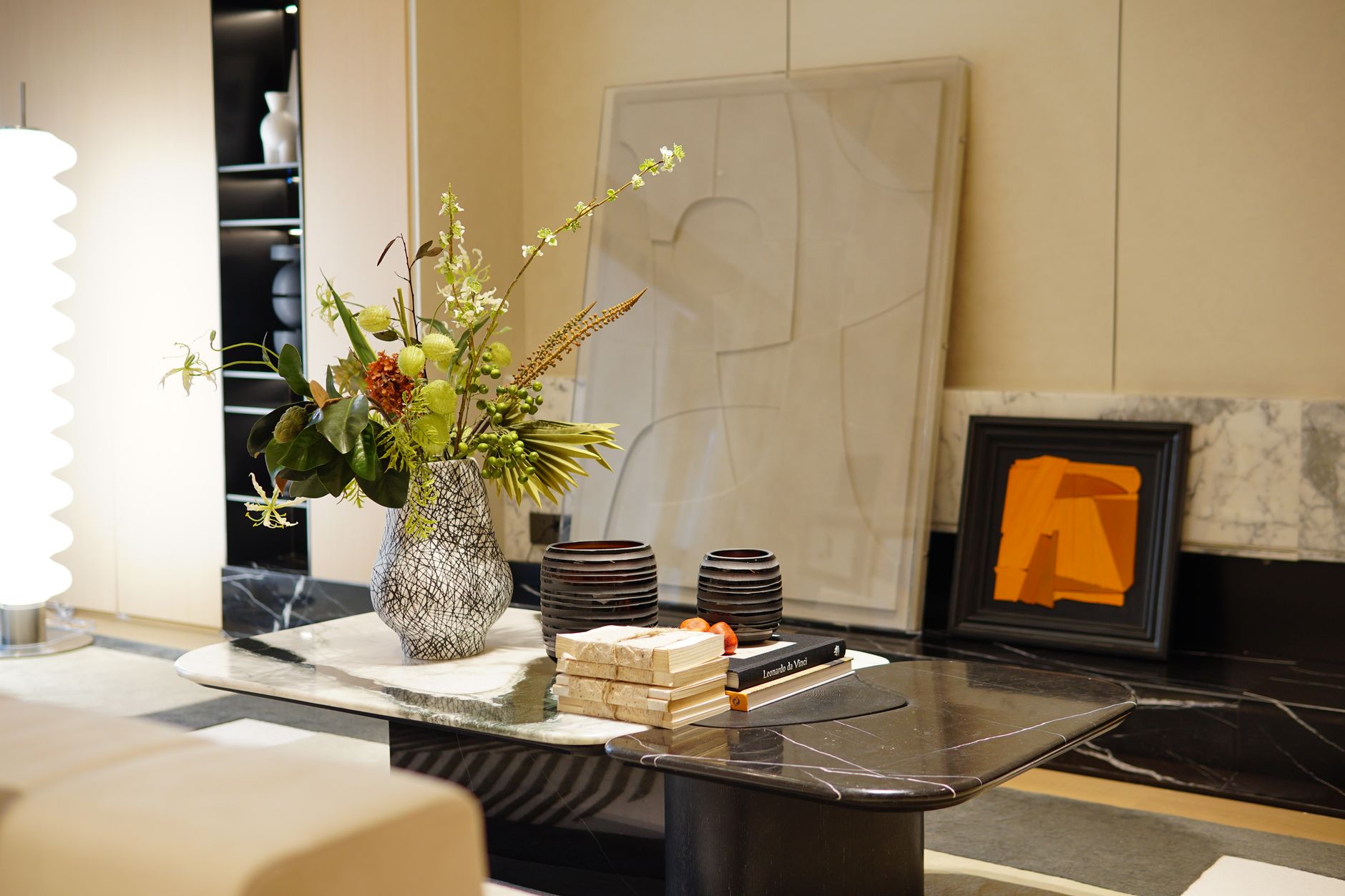 A stylish modern interior with a marble table featuring a decorative flower vase and artwork.
