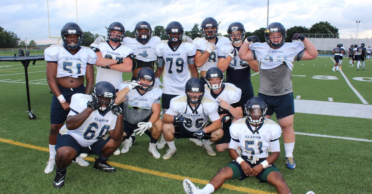 Group of football players in uniforms posing on a sports field.