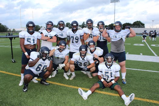Group of football players in uniforms posing on a sports field.