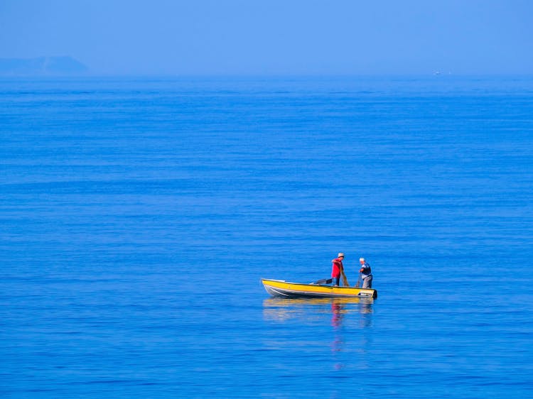 Two People Riding Yellow Boat On Blue Sea