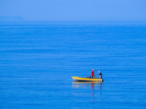 Free Two people enjoying a serene boat ride on the blue sea near Himarë, Albania. Stock Photo