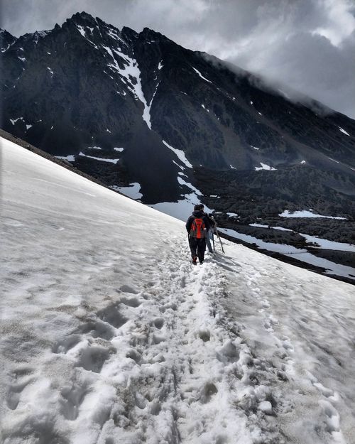 Free Two climbers trekking a snowy mountain path under cloudy skies, showcasing winter adventure. Stock Photo