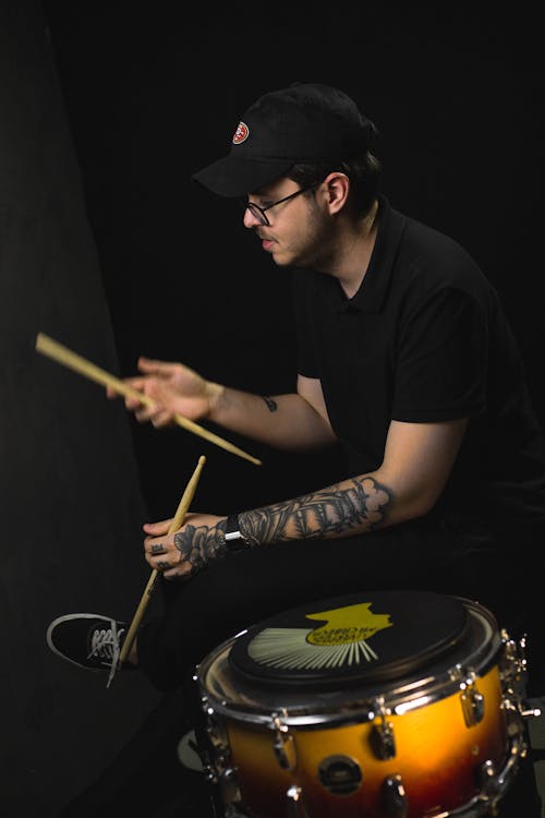 A Man in Black Shirt Playing Drums