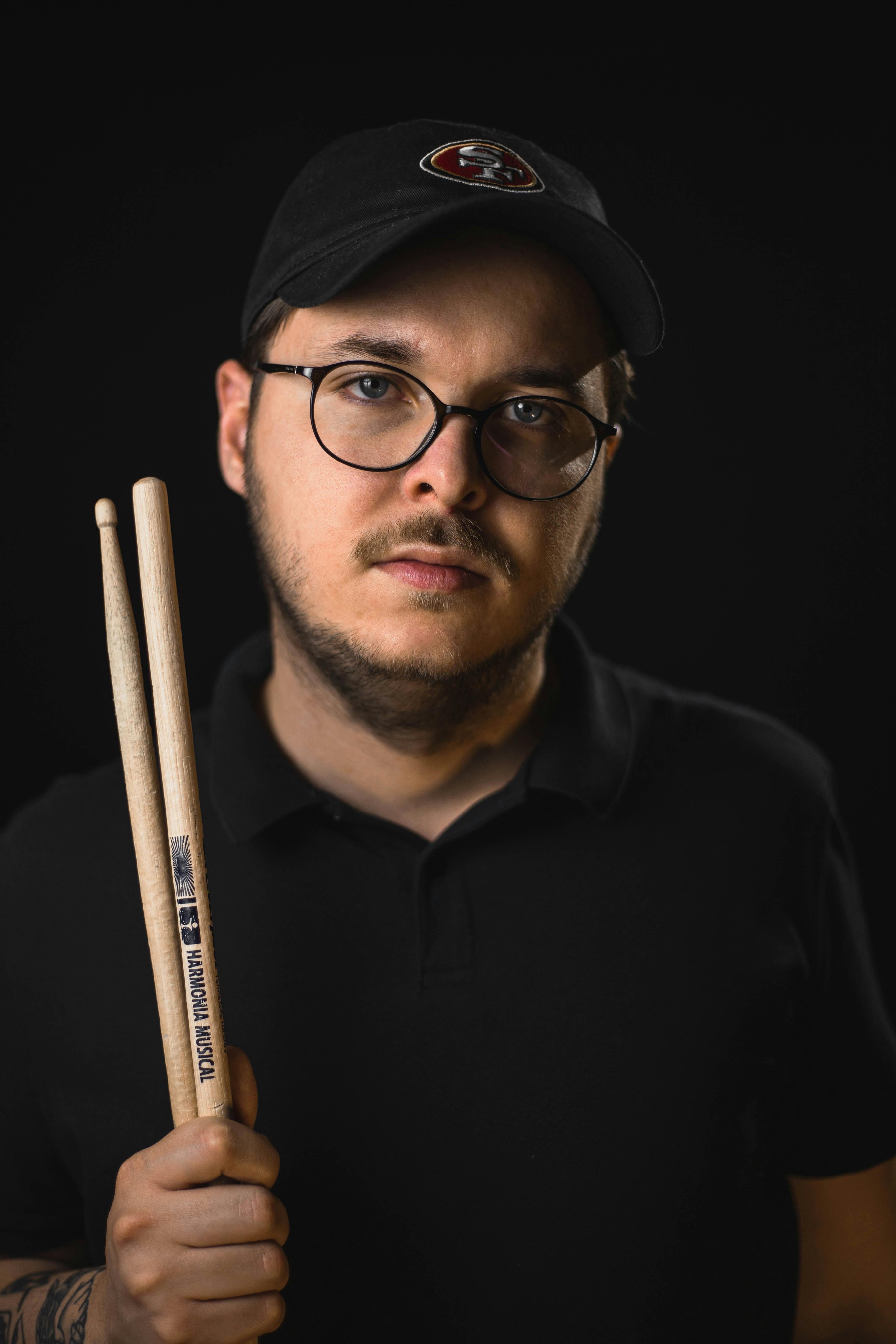 Focused portrait of a male drummer holding drumsticks, emphasizing his passion for music.