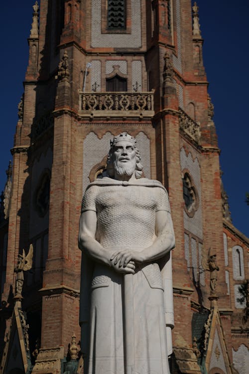 Gray Man Statue near Brown Brick Building