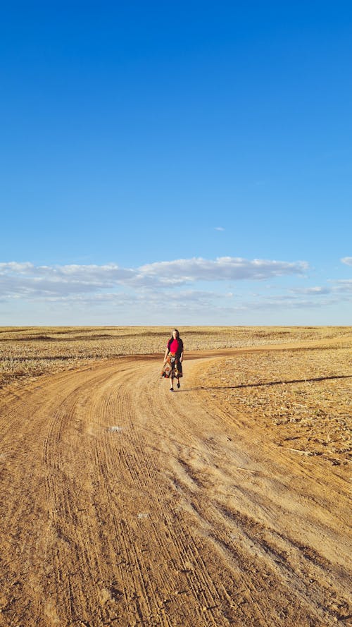 A Woman Walking on the Brown Sand Under Blue Sky