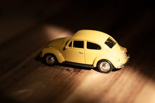 Close-Up Shot of a Yellow Toy Car on Wooden Surface