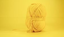 Close-up image of a yellow wool yarn ball against a vivid yellow background, perfect for crafting themes.