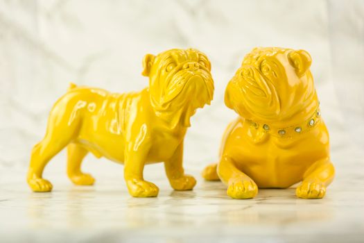 A pair of vibrant yellow bulldog sculptures on a marble background, perfect for modern decor.