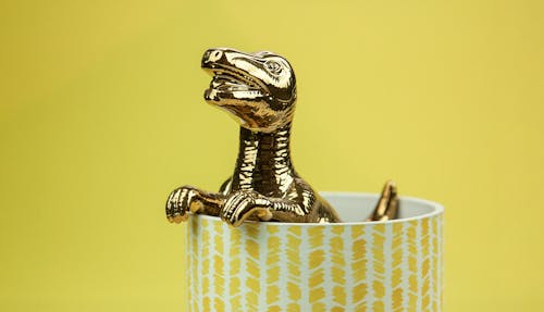 A Gold Dinosaur Figurine in a Cup