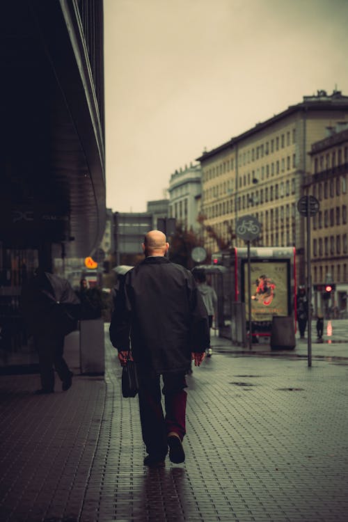 A Man in a Black Jacket Walking on a Street