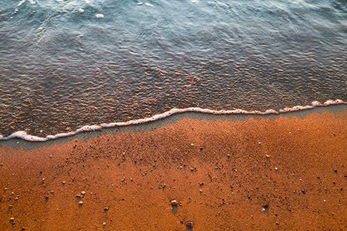 Free Calm ocean waves gently lapping at a sandy shore during a tranquil sunset. Stock Photo