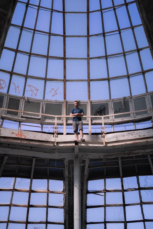 Free Man standing on platform in abandoned industrial building with large glass windows. Stock Photo