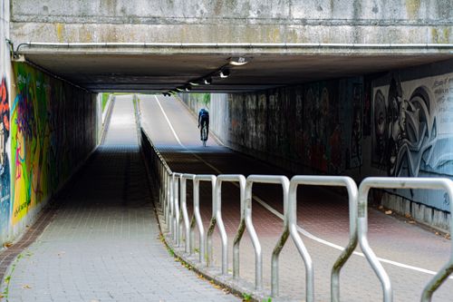 Free A cyclist rides through a vibrant graffiti-adorned tunnel in an urban setting. Stock Photo