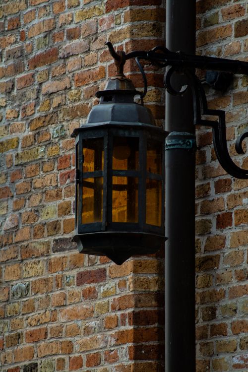 Free A classic lantern attached to a brick wall in Bruges, Belgium, showcasing vintage charm. Stock Photo