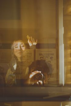 Artistic reflection photo with a woman and photographer in golden light, creating a warm composition.
