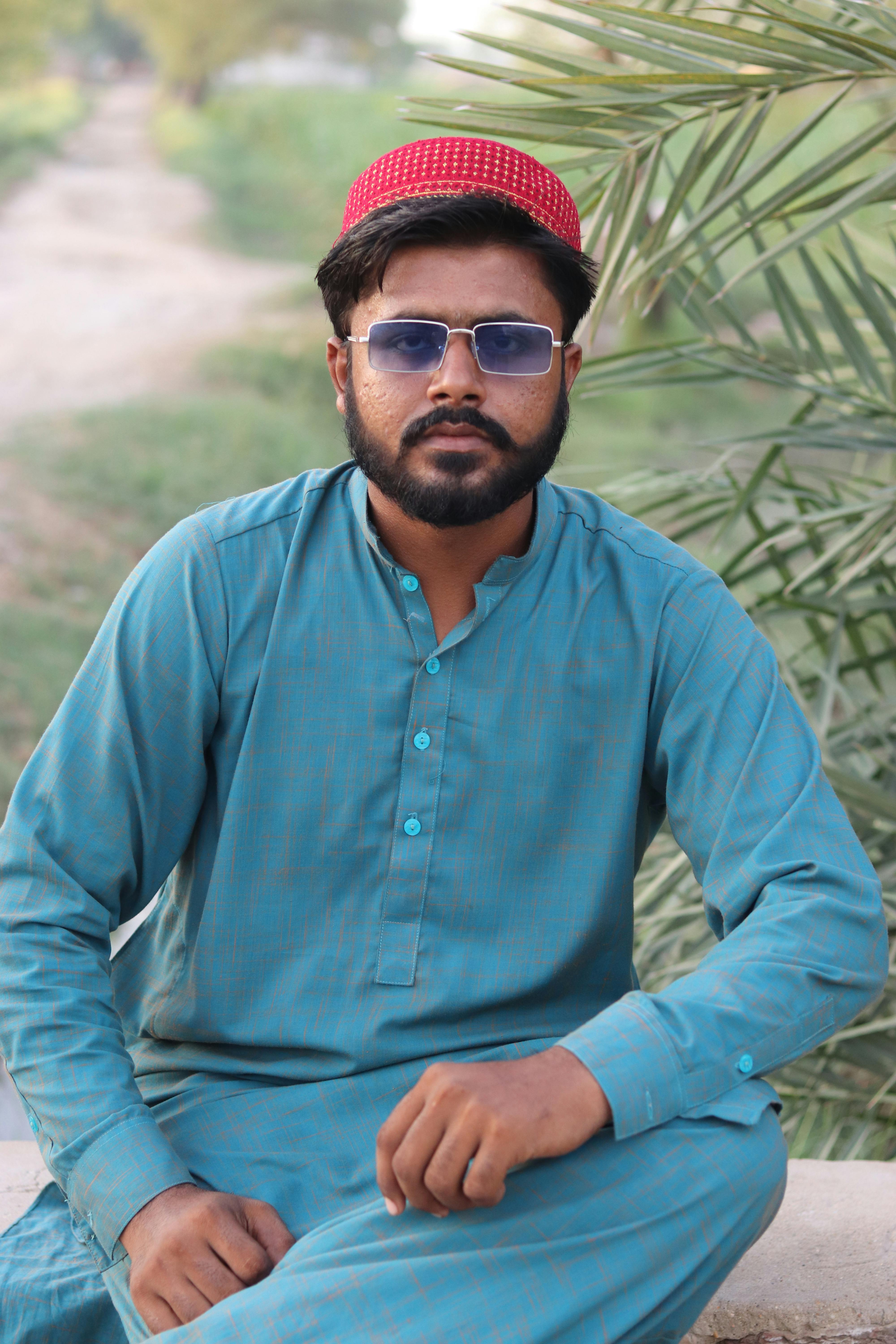 A man wearing traditional clothes and sunglasses poses outdoors. Vibrant and relaxed vibe.