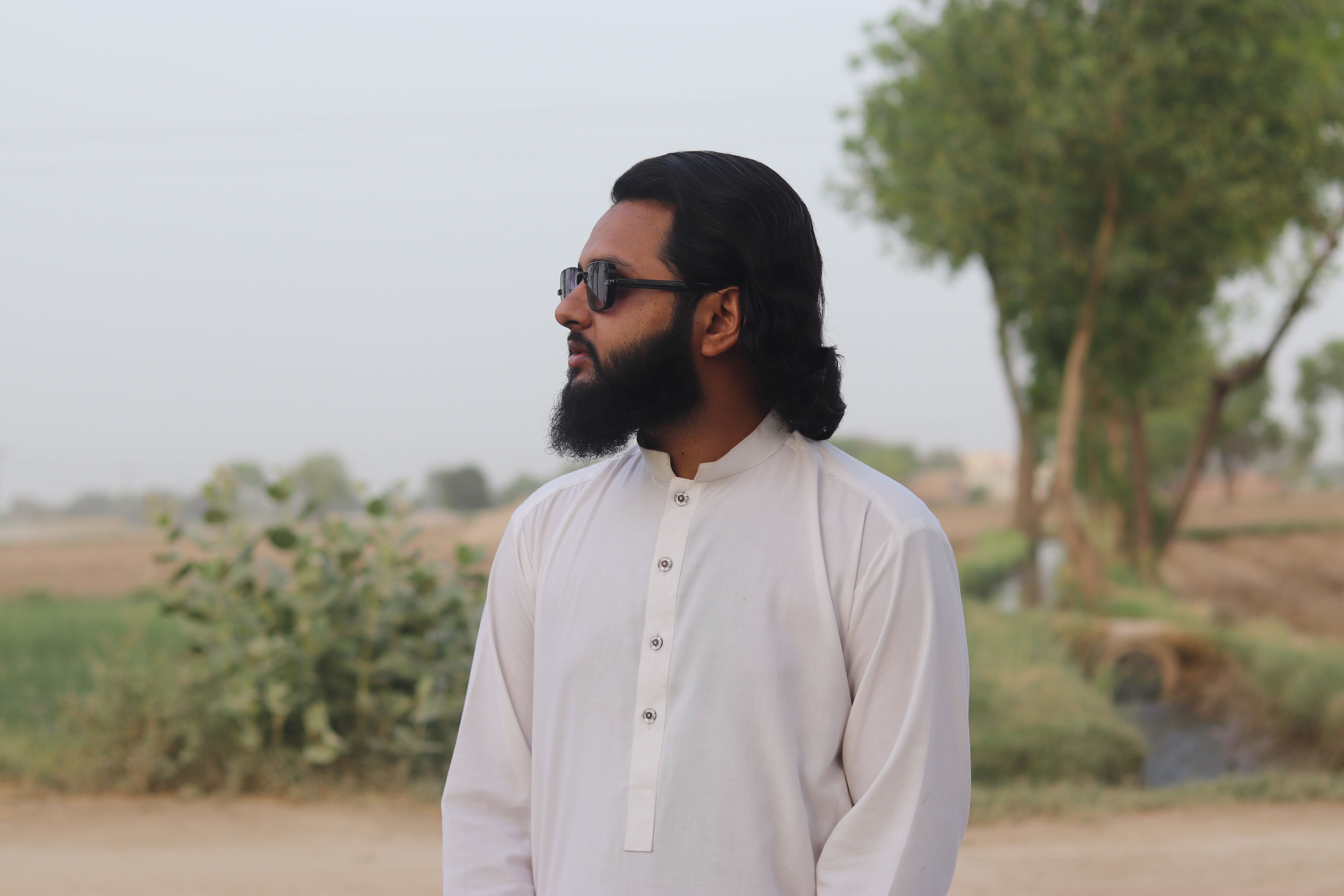 Portrait of a man with sunglasses outdoors, showcasing cultural attire.