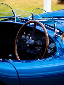 Detailed view of the dashboard and steering wheel of a blue luxury convertible.