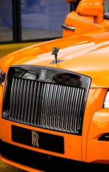 Close-up of a luxurious orange Rolls Royce highlighting its iconic grille.