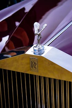 Close-up of the iconic Rolls-Royce Spirit of Ecstasy emblem on a luxury car hood.