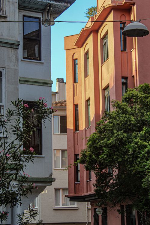 Free Urban street view featuring colorful building facades during daytime, framed by greenery. Stock Photo