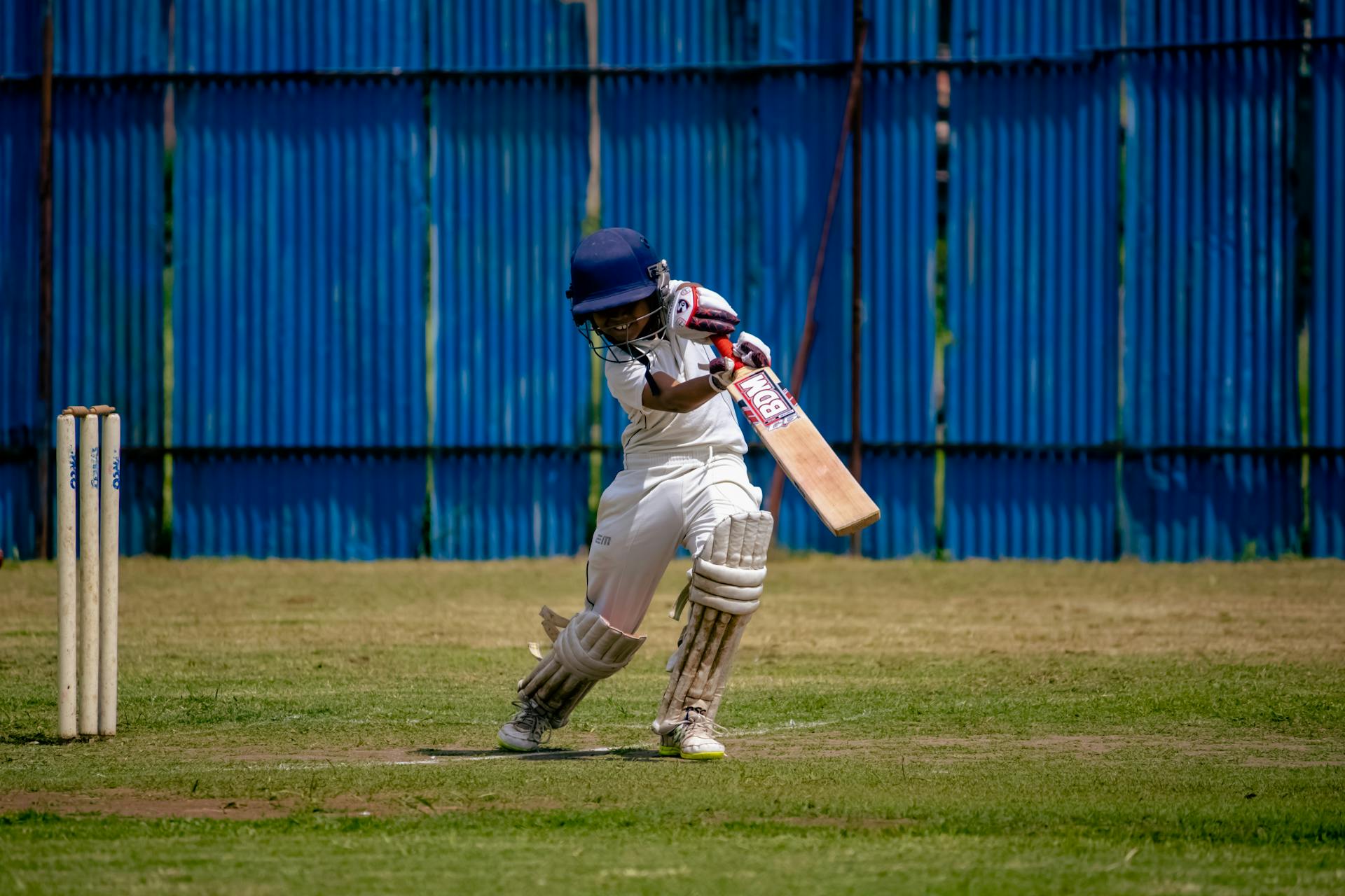 Young cricketer in action on a sunny day at a field in Gahunje, MH, India.