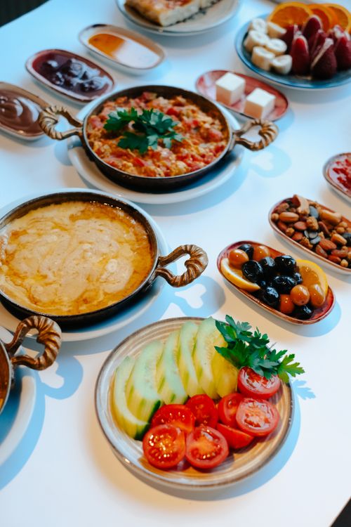 Free Gourmet breakfast spread featuring fresh fruits, nuts, and savory dishes on a white table. Stock Photo