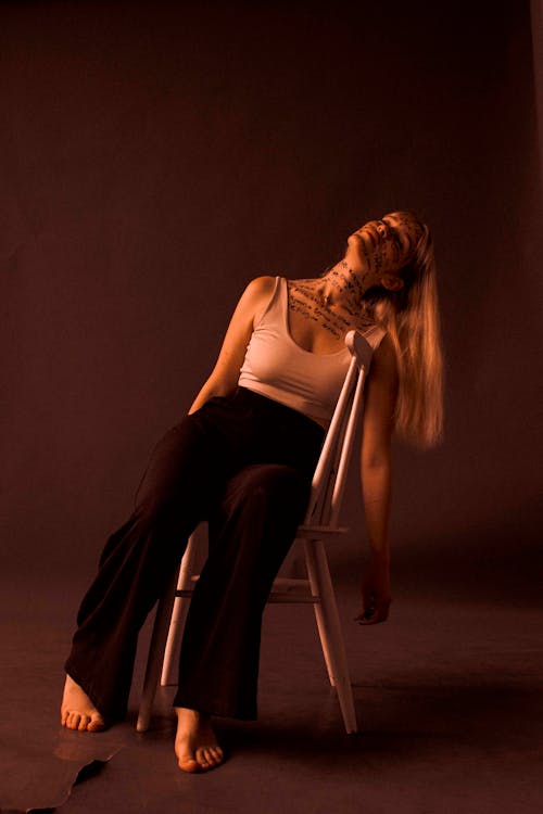 Woman in WHite Tank Top sitting on a Chair 