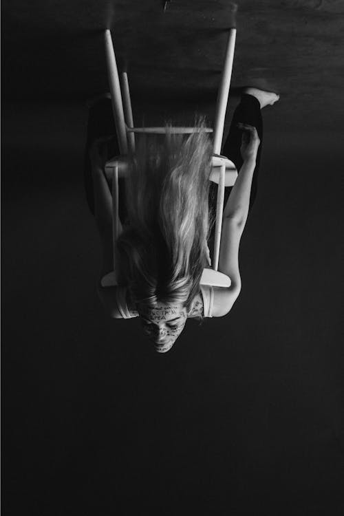 Grayscale Photo of Woman sitting on Chair in an Upside Down Shot 