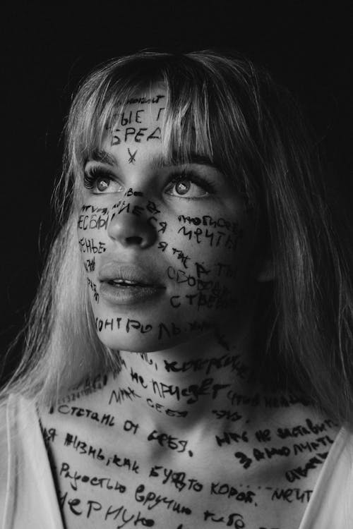 Grayscale Photo of Woman With Written Words on Her Face and Body