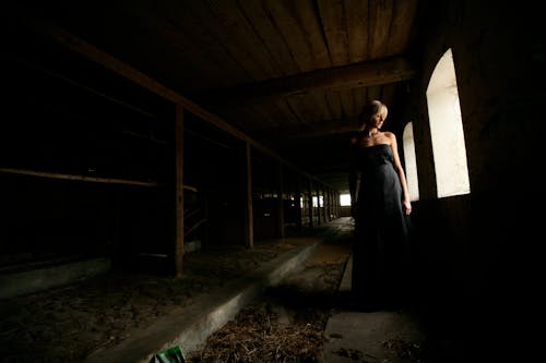 бесплатная Женщина, стоящая возле открытого окна внутри комнаты Стоковое фото