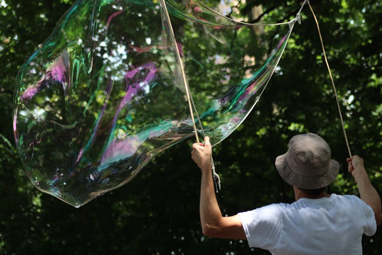 A Person Holding Sticks With A Big Bubble 