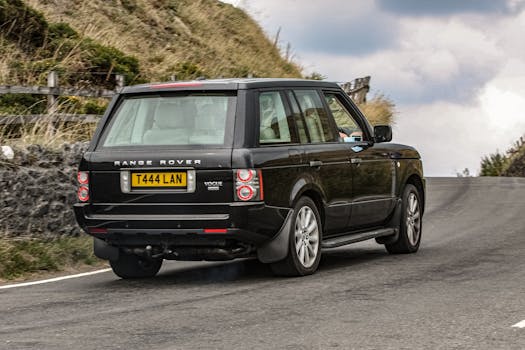 Black Range Rover cruising through a picturesque mountain road, epitomizing travel adventure.