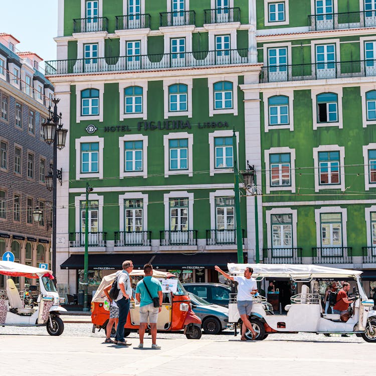 People On The Street Beside Green And White Building